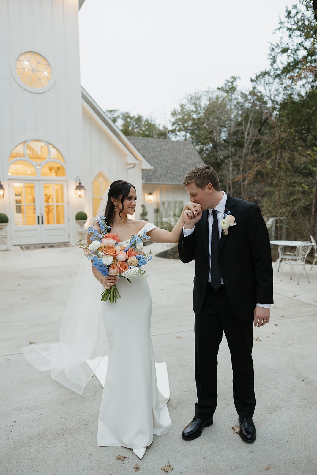 Pearson kissing Avery’s hand in front of the lit chapel at dusk