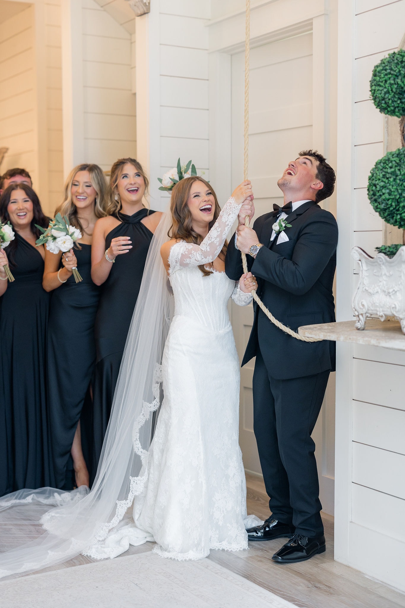 Catherine and Kade laughing together as they ring the chapel bell after their ceremony at The French Farmhouse Venue