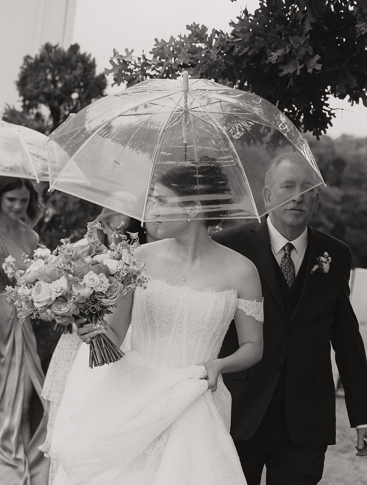 Black and white photo of Elizabeth walking with her father under an umbrella