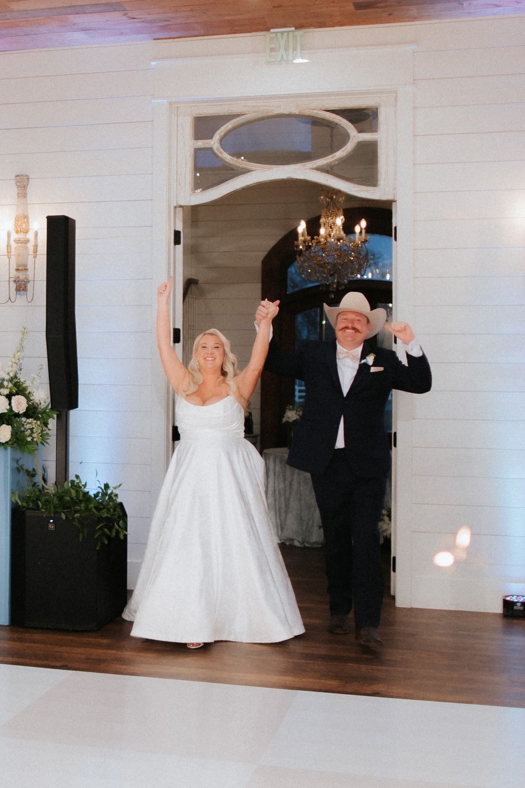 Kara and Anthony making their grand entrance into the reception hall with hands raised and huge smiles
