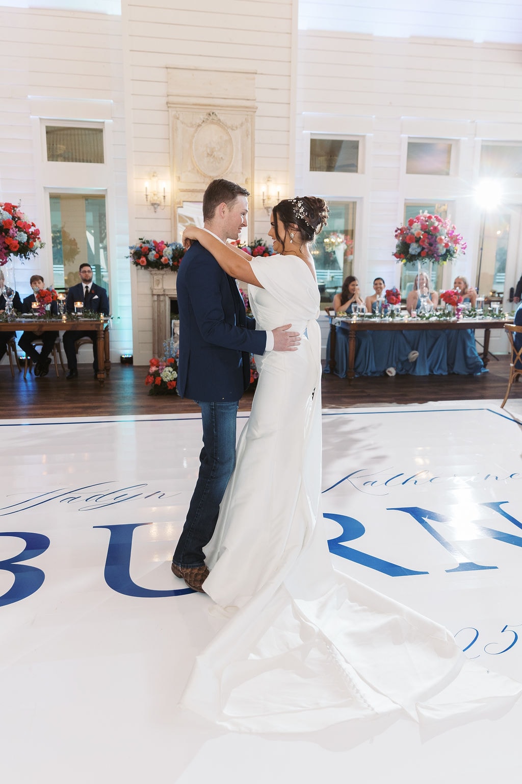 Katherine and Hayden sharing their first dance on a custom monogram dance floor