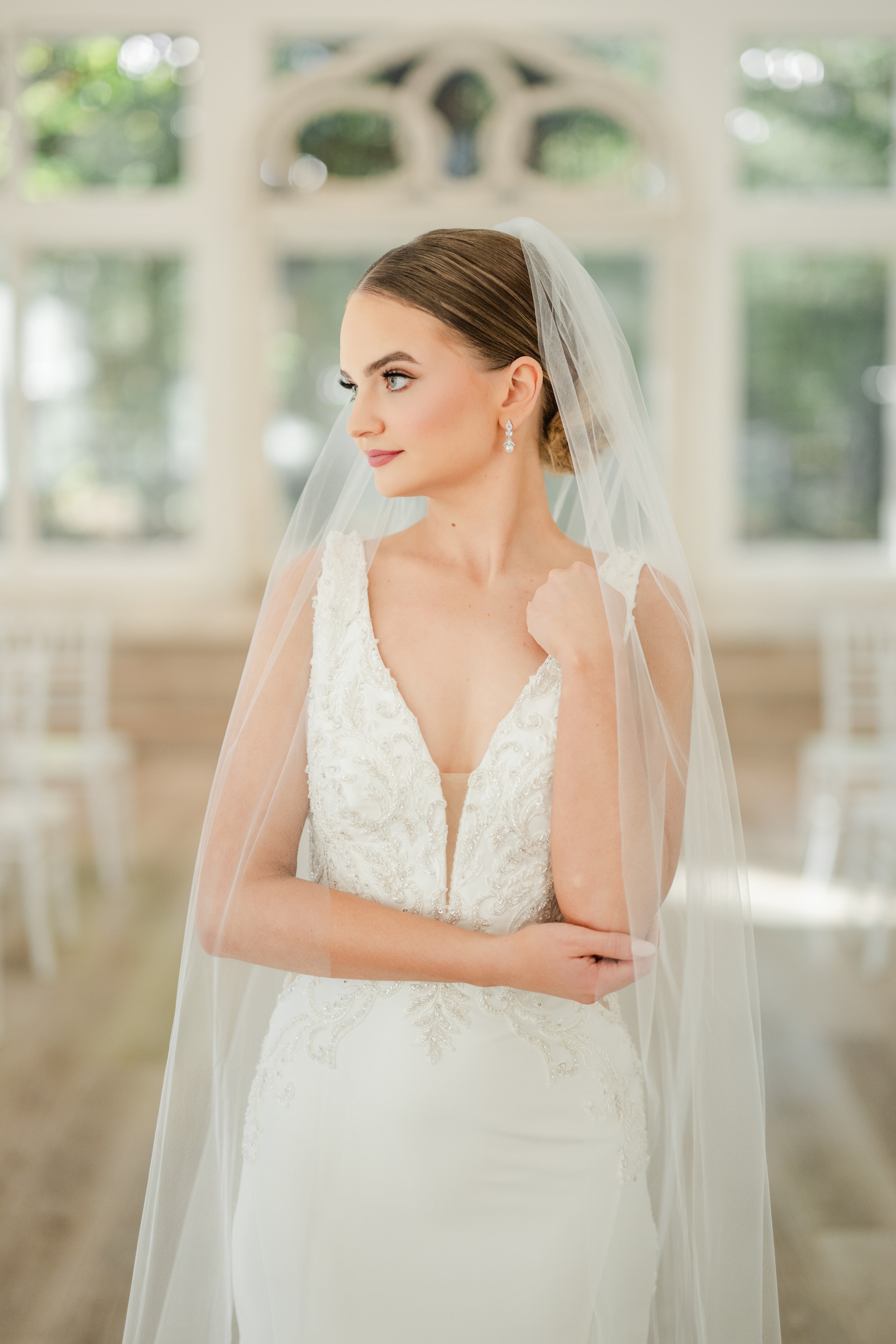 Bride in a beaded lace gown with cathedral veil posing inside The French Farmhouse reception hall