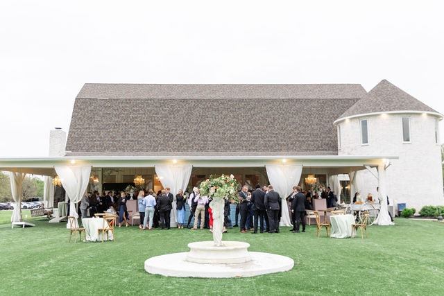 Bride and groom mingling with guests under the covered pavilion chandelier during cocktail hour
