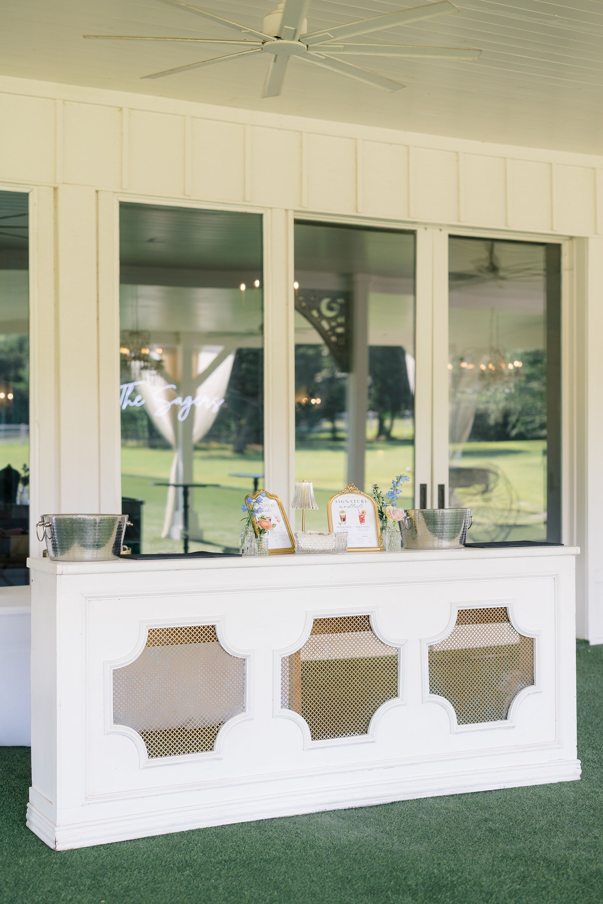 Wide view of guests enjoying cocktail hour on the lawn under the white pavilion with draping curtains