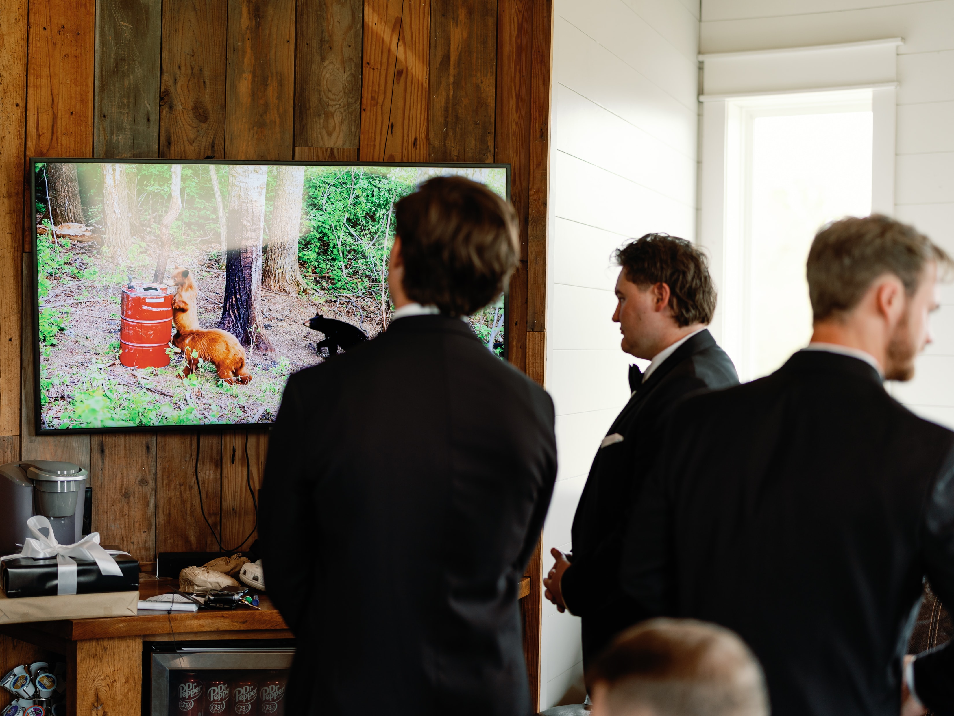 Groomsmen in tuxedos watching hunting footage on the TV in the Groom's Room